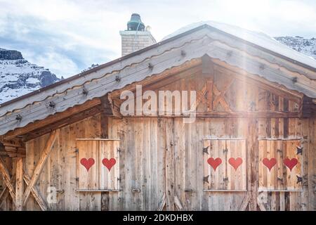 wooden building in alpine style with shutters decorated with red hearts, dolomites, belluno, italy Stock Photo