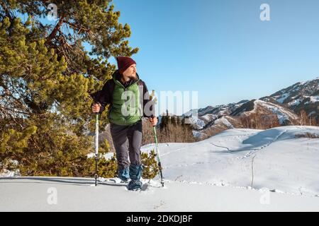 Un jeune homme se balade au milieu de neige blanche. Dans ses mains sont les bâtons de trekking. Le tourisme de montagne d'hiver. Kazakhstan Banque D'Images