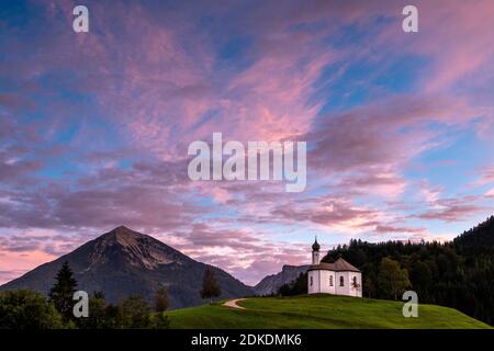 La petite Annakircherl, petite chapelle sur une colline à Achenkirch, sur la Rend des Karwendel dans les Alpes, Tyrol après le coucher du soleil. Les tons violet et bleu dominent le ciel du soir. En arrière-plan les montagnes. Banque D'Images