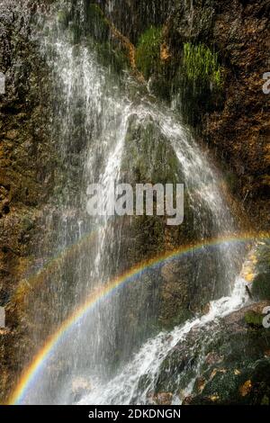 Arc-en-ciel à la cascade de Dalfaz sous la Dalfaz via ferrata sur l'Achensee dans les montagnes Rofan. L'eau tombe sur la face rocheuse et forme un merveilleux petit arc-en-ciel double au soleil. Banque D'Images