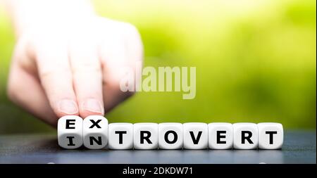 La main tourne les dés et change le mot introvert en extrovert. Banque D'Images