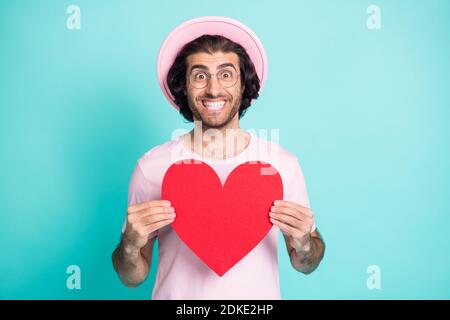 Portrait d'un homme optimiste cool montrant le papier coeur porter rose lunettes pour t-shirt à capuchon isolées sur fond bleu sarcelle Banque D'Images