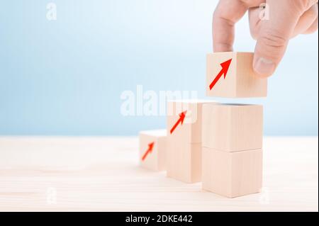 Bloc de bois à disposition manuelle avec icône de flèche vers le haut. Main de personne coupée sur la table. Processus de réussite de la croissance du concept d'entreprise. Banque D'Images