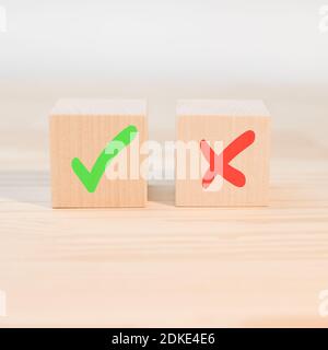 Concept de prise de décision positive ou négative ou choix d'approbation ou de rejet. Marque de graduation et croix x sur les cubes en bois. Blocs en bois avec gre Banque D'Images