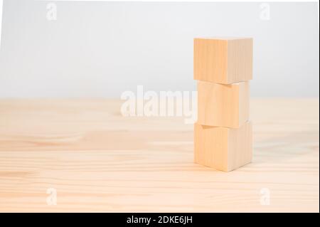 trois cubes en bois pour votre texte, vos icônes, votre signe et vos symboles pour créer vos concepts créatifs. Maquette de cubes en bois vierges. Blocs sur table en bois Banque D'Images