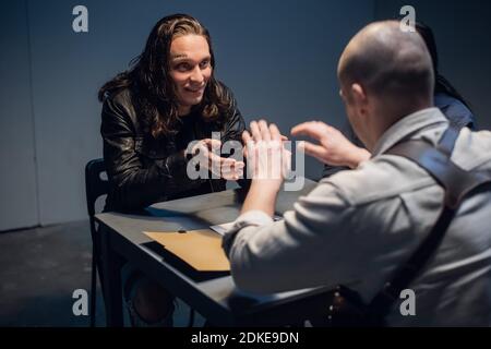 Un homme aux cheveux longs avec des tatouages sur son visage est soupçonné de commettre un crime et est interrogé. Banque D'Images