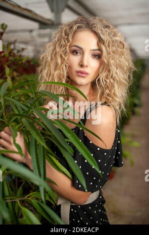 portrait d'une belle jeune fille debout parmi des plantes vertes regarder l'appareil photo et sourire Banque D'Images