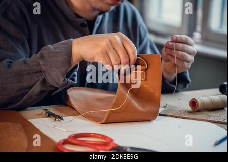 Bureau dans l'atelier du cordonnier. Le processus de fabrication des chaussures en cuir. Gros plan des mains sans visage. Banque D'Images