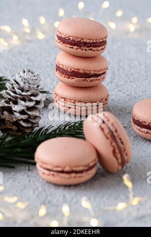 Macarons de figue empilés sur une table blanche, décorés l'hiver avec des branches de sapin et des cônes de pin, un anneau de lumière brille en arrière-plan Banque D'Images