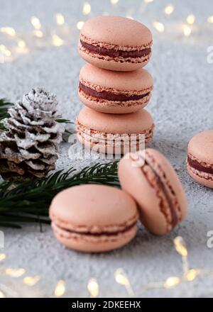 Macarons de figue empilés sur une table blanche, décorés l'hiver avec des branches de sapin et des cônes de pin, un anneau de lumière brille en arrière-plan Banque D'Images