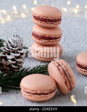 Macarons de figue empilés sur une table blanche, décorés l'hiver avec des branches de sapin et des cônes de pin, un anneau de lumière brille en arrière-plan Banque D'Images