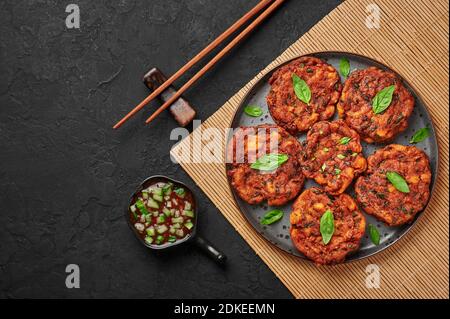 TOD Mun Pla ou des gâteaux de poisson thaïlandais sur une assiette noire sur une table en ardoise sombre. Plat de cuisine traditionnelle thaïlandaise. Plats et repas asiatiques. Copier l'espace. Vue de dessus Banque D'Images