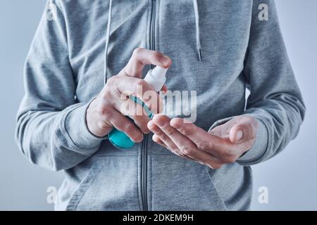Hands disinfecting with sanitizer spray, close up with selective focus Stock Photo