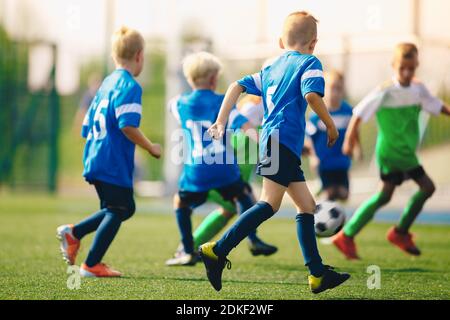 Jeu de football Kicking pour Garçon sur le terrain de l'école. Jeunes joueurs de sport anonymes jouant au football lors d'une journée d'été Banque D'Images