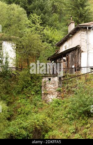 Maisons et dépendances (hangars) dans le village de Mugla en conifères Forêt sur les pentes abruptes des montagnes Rhodope dans Mauvais temps nuageux (Rhodop Banque D'Images