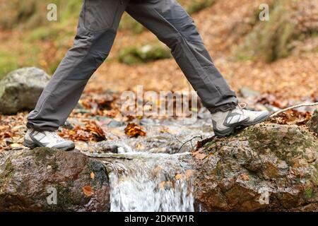 Vue latérale en gros plan d'un passage à pied des jambes de trekker une rivière en hiver Banque D'Images