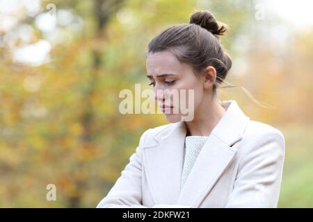 Mélancholique triste femme regardant en marchant seule dans un parc en hiver Banque D'Images
