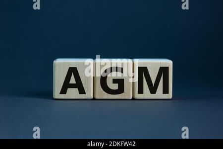 Symbole AGM. Mot concept 'AGM' - 'Assemblée générale annuelle' sur des cubes sur une belle table en bois. Arrière-plan blanc. Affaires et assemblée générale annuelle Banque D'Images
