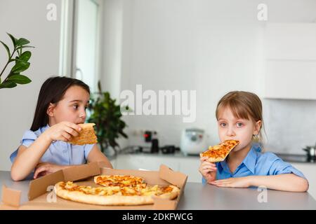 Deux petites filles amies joyeuses qui mangent des tranches de pizza. Banque D'Images