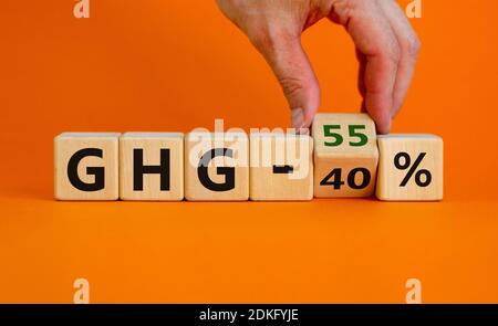 2030 symbole de changement de gaz naturel. La main retourne un cube et change les mots « GHG 40 pour cent » en « GHG 55 pour cent ». Magnifique fond orange, copie s Banque D'Images