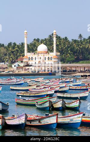 Port de pêche avec des bateaux colorés dans la mer d'Arabie avec la mosquée en arrière-plan le matin ensoleillé tôt (Kerala, Inde) Banque D'Images