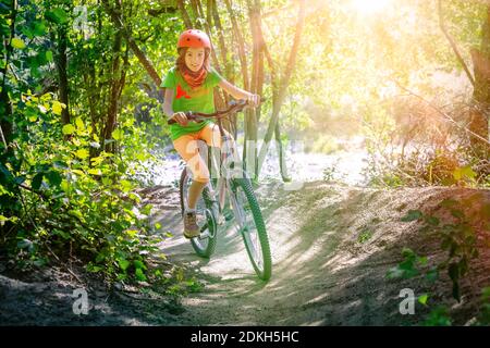 Italie, Vénétie, Belluno, Agordino, petite fille (10 ans) s'amuse avec sa bicyclette le long d'un chemin forestier Banque D'Images