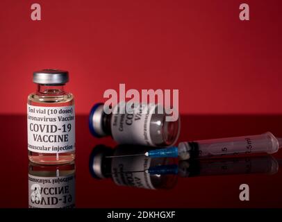 Petite bouteille de vaccin contre le coronavirus sur table en verre réfléchissant avec seringue prête pour la vaccination Banque D'Images