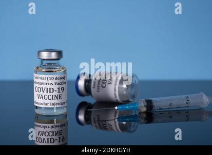 Petite bouteille de vaccin contre le coronavirus sur table en verre réfléchissant avec seringue prête pour la vaccination Banque D'Images