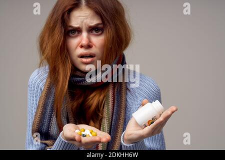 femme malade avec des pilules dans ses mains vitamines fond gris écharpe chaude Banque D'Images