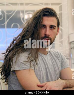 Beau, jeune modèle mâle barbu avec de longs cheveux posant à l'intérieur. Style, tendances, mode concept. Banque D'Images
