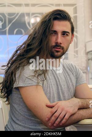 Beau, jeune modèle mâle barbu avec de longs cheveux posant à l'intérieur. Style, tendances, mode concept. Banque D'Images