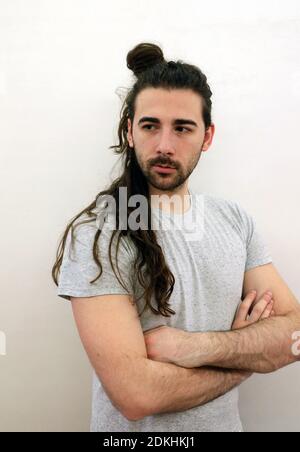 Beau, jeune modèle mâle barbu avec de longs cheveux posant à l'intérieur. Style, tendances, mode concept. Banque D'Images