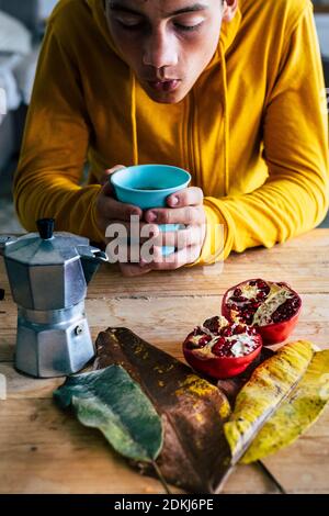 Les jeunes prennent le petit-déjeuner à la maison avec du café en automne concept de fond de composition - couleurs rouge et jaune et femelle tenir une tasse de café sur une table en bois Banque D'Images