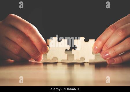 La personne tient deux pièces de puzzle avec ses doigts. Banque D'Images