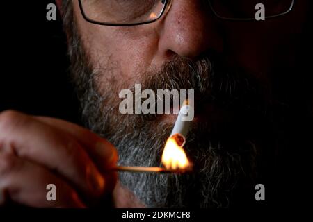 Marseille, France. 14 décembre 2020. Dans cette illustration, un homme allume une cigarette.comme le prévoit le gouvernement français, le prix moyen d'un paquet de cigarettes sera de 10 cents plus cher. La décision a été prise dans l'espoir de réduire le nombre de fumeurs en France. Crédit : SOPA Images Limited/Alamy Live News Banque D'Images