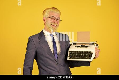 Objets anciens du vendeur. Connaisseur des valeurs vintage. Machine à écrire vintage. Les vieux habitudes de l'auteur de bâton. Les hommes d'affaires utilisent la technologie rétro. Homme mûr teint les cheveux de barbe fond jaune. Magasin de marchandises d'occasion. Banque D'Images