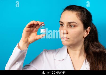 Un médecin ou un technicien de laboratoire détient un vaccin contre la polio sur fond bleu. Vaccination et prévention poliomyélite. Paralysie infantile. Banque D'Images