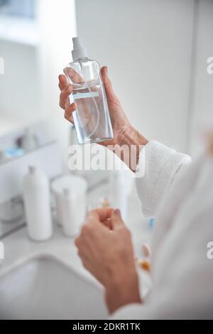 Image focalisée d'une belle main de femme avec bouteille à la main dans la chambre à l'intérieur Banque D'Images