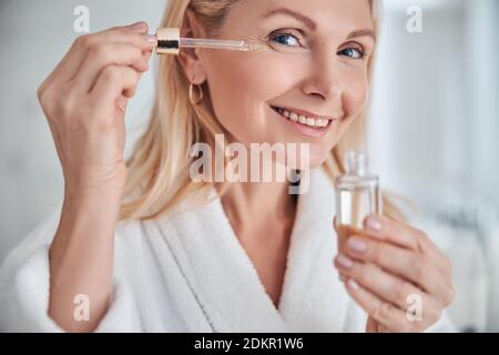 Huile cosmétique appliquée sur le visage de la jeune femme Banque D'Images