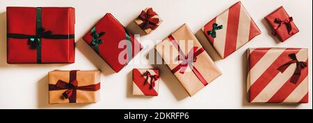 Ensemble de boîtes-cadeaux de fête en papier d'emballage décorées de noeuds en ruban vert et rouge sur fond blanc Uni, vue du dessus, composition horizontale. Concept de Noël après-Noël Banque D'Images