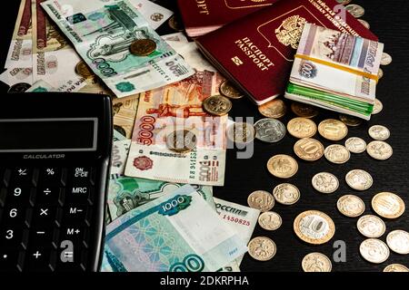 il y a des pièces de monnaie, de l'argent papier et deux passeports internationaux une inscription de table en bois noir passeport fédération de russie Banque D'Images