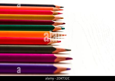 de nombreux crayons de couleur aiguisés se trouvent sur une table en bois blanc Banque D'Images