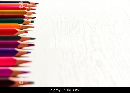 de nombreux crayons de couleur aiguisés se trouvent sur une table en bois blanc Banque D'Images