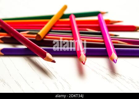 de nombreux crayons de couleur aiguisés se trouvent sur une table en bois blanc Banque D'Images