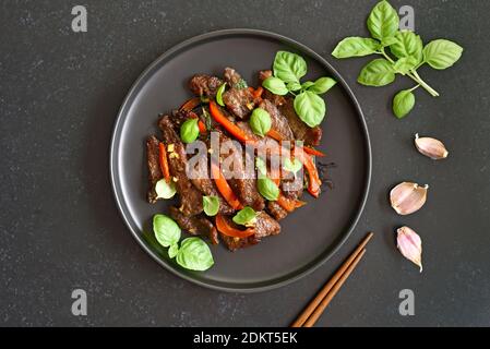 Bœuf sauté de style thaïlandais avec légumes sur plaque sur fond de pierre sombre. Vue de dessus, plan d'appartement Banque D'Images