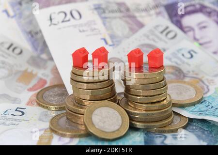 Photo du dossier datée du 12/09/18 de maisons modèles sur un tas de pièces de monnaie et de billets de banque. Le prix moyen de l'immobilier britannique a atteint un sommet record de ??245,000 en octobre, selon les chiffres de l'Office for National Statistics (ONS). Banque D'Images