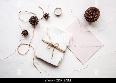 Pose plate style hygge. Liste de souhaits de Noël. Papier fait à la main noué avec des fils artisanaux. Enveloppe de lettre, cônes de pin, fil de métier. Banque D'Images