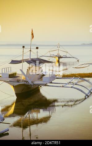 Les bateaux de pêche philippins traditionnels, connus sous le nom de bateaux de pêche « bangka » ou de bateaux à pompe, n'ont pas de quille et sont construits de cette façon pour dériver au-dessus des mers peu profondes et des récifs coralliens. Ils sont équipés de deux stabilisateurs pour offrir un soutien sur les mers difficiles. Les bateaux Bangka ont maintenant des rôles allant du transport de marchandises aux îles éloignées, en passant par les taxis touristiques, les bateaux d'expédition de plongée et les ferries. Photo : des bateaux bangka amarrés à Buyong, sur l'île Mactan, à Cebu, aux Philippines. Banque D'Images