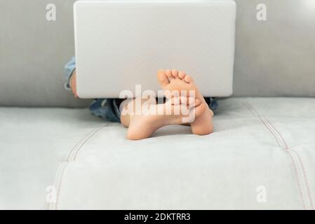 Apprentissage à distance pendant l'isolement pendant la quarantaine chez le coronovirus. Garçon et ordinateur portable à la maison. Style de vie Banque D'Images