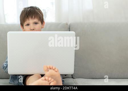 Apprentissage à distance pendant l'isolement pendant la quarantaine chez le coronovirus. Garçon et ordinateur portable à la maison. Style de vie Banque D'Images